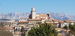 eine Stadt mit einem Uhrturm auf einem Berg in der Unterkunft Gîte Le Logis Vallat haut in Fuveau