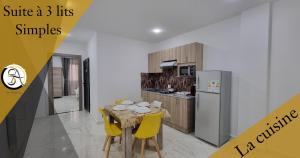 Hostel SA Bab Ezzouar في لي ليدو: مطبخ مع طاولة وكراسي وثلاجة