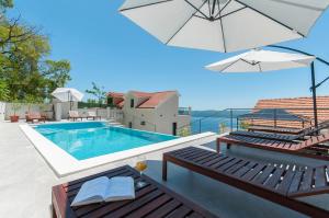 a swimming pool with two chairs and an umbrella at XXL Villa Vista - Heated Pool in Lokva Rogoznica