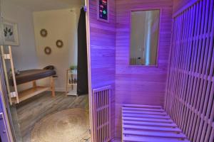 Cette chambre est dotée d'un mur violet et d'une porte. dans l'établissement *Au Sauna de Maintenon*, à Maintenon