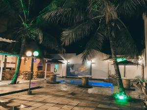 a resort with palm trees and a pool at night at Hotel Sanches in São Mateus