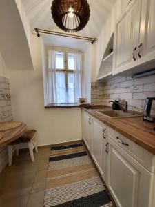 a kitchen with white cabinets and a sink and a window at Downtown Romantic in Székesfehérvár +15 photos
