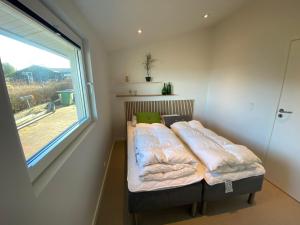 małe łóżko w pokoju z oknem w obiekcie Strandhuset. w mieście Asperup