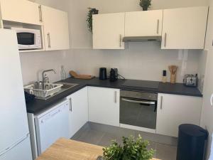 a kitchen with white cabinets and a sink at Appart T3 Standing - Terrasse - 2 Parkings in Montpellier