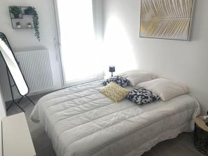 een wit bed in een kamer met kussens erop bij Appart T3 Standing - Terrasse - 2 Parkings in Montpellier
