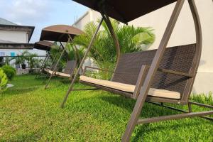 deux chaises assises dans l'herbe sous un parasol dans l'établissement Luxurious Studios, à Douala