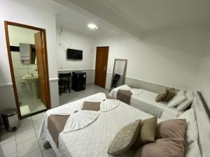 Habitación de hotel con 2 camas y espejo en Hotel Caiçara, en Cachoeiro de Itapemirim