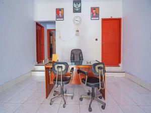 um quarto com uma mesa de madeira e 3 cadeiras em OYO 92337 Wisma Arwini Syariah em Sinjay