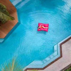 a person laying in a red chair in the water at Diamond Resort Phuket Bangtao in Phuket