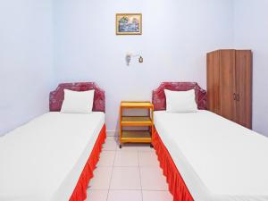 um quarto com 2 camas e um armário de madeira em OYO 92337 Wisma Arwini Syariah em Sinjay