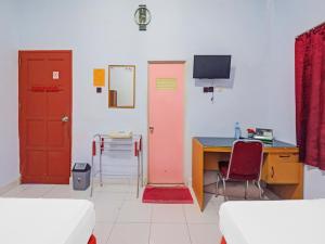um quarto com duas portas e uma secretária com um computador em OYO 92337 Wisma Arwini Syariah em Sinjay
