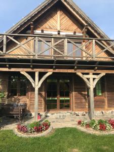 a large wooden house with flowers in front of it at Dom Nad Jeziorem Łąkorz in Łąkorz