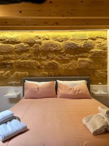 1 cama con almohadas rosas frente a una pared de ladrillo en LA FORMICA APARTMENT, en Agrigento