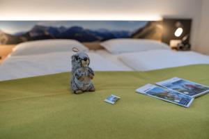 a stuffed animal sitting on a bed next to a book at Haus Holzeck in Schönau am Königssee