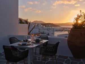 a table and chairs on a balcony with the sunset at Ariti Seaside Residence in Naousa