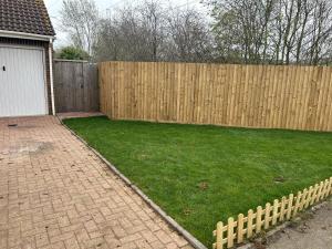 a backyard with a wooden fence and a green yard at Newly refurbished charming 3-Bed House in Barking in Barking