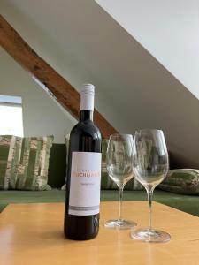 uma garrafa de vinho sentada numa mesa com dois copos de vinho em Penzion Viktoria em Znojmo