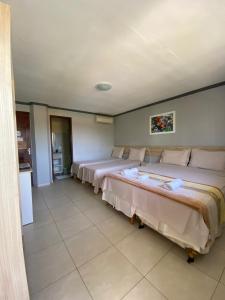 タマンダレーにあるPousada Pérola do Marのベッド2台とキッチンが備わる客室です。