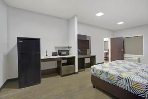 Schlafzimmer mit einem Bett und einem Schreibtisch mit einer Mikrowelle in der Unterkunft Motel 6-Monahans, TX in Monahans