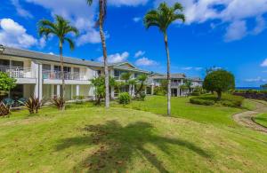 a house with palm trees and a yard at Emmalani Court 414 in Princeville