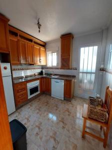 una cocina con armarios de madera y electrodomésticos blancos en Casa Castillo Penthouse with balcony and solarium near La Zenia boulevard en Orihuela