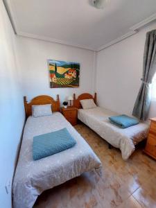 a bedroom with two beds and a painting on the wall at Casa Castillo Penthouse with balcony and solarium near La Zenia boulevard in Orihuela