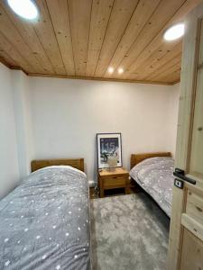 a bedroom with two beds and a wooden ceiling at Megeve centre in Megève