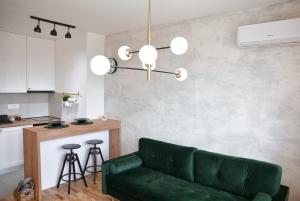 Il comprend un salon avec un canapé vert et une cuisine. dans l'établissement CROWN apartment, à Subotica