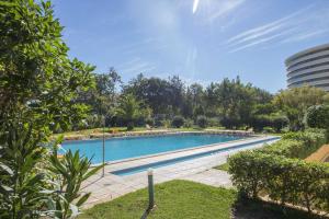 une grande piscine dans un parc arboré dans l'établissement Apartamento Valerie, à Vilamoura