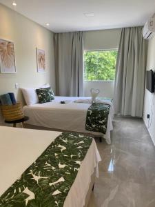um quarto de hotel com duas camas e uma janela em Santorini Beach Hotel em Arraial d'Ajuda