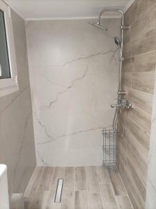 W łazience z marmurową ścianą znajduje się prysznic. w obiekcie Calypso w Atenach