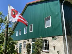 un edificio verde con una bandera delante de él en FeWo Diekshörn an der Nordsee Elbe am Nord-Ostsee-Kanal, en Ramhusen