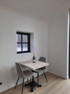 a white table with two chairs and a bottle of wine on it at Komo Hill Stays - guestroom Komo Cosy in Kruisem