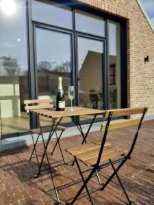 a picnic table with a bottle of wine and two glasses at Komo Hill Stays - guestroom Komo Cosy in Kruisem