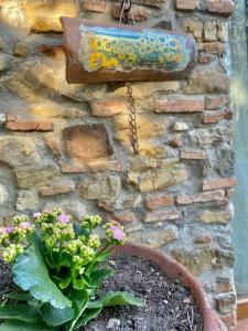 un panneau sur un mur de pierre avec une plante en pot dans l'établissement Berenice in Chianti, à Bagno a Ripoli