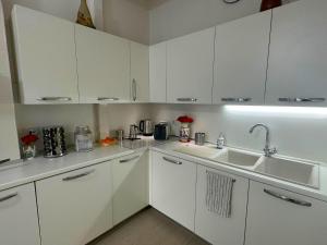 uma cozinha branca com armários brancos e um lavatório em Modern River House em Florença