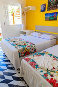 two beds in a room with yellow walls at Pousada Summer Beach by AFT in Porto De Galinhas