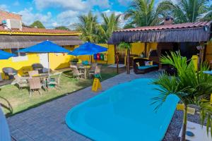 a pool in the yard of a house with chairs and umbrellas at Pousada Summer Beach by AFT in Porto De Galinhas