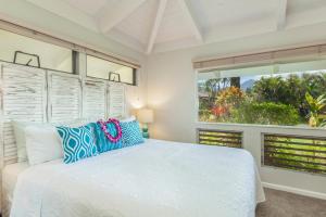 a bedroom with a white bed and two windows at Mala Hale in Princeville