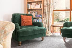 uma cadeira verde com uma almofada laranja na sala de estar em Byre Cottage Woodland Coniston em Torver