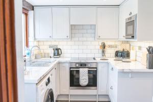 a white kitchen with white cabinets and a dishwasher at Millers Cottage Woodland Coniston in Torver