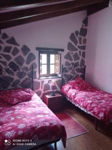 1 dormitorio con 2 camas y ventana en Casa Capricho, en Proaza