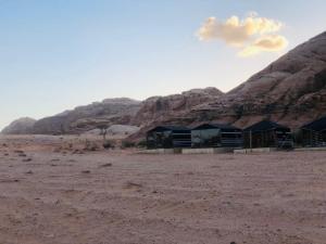 a lodge in the desert with mountains in the background at Wadi Rum Moon Camp in Wadi Rum