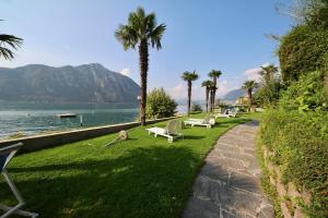 une rangée de bancs assis sur l'herbe près de l'eau dans l'établissement Luganersee, Pool, Strand, Parkplatz, Suite, à Bissone