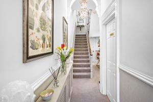 a hallway with a staircase with a vase of flowers at Sandway House in Torquay