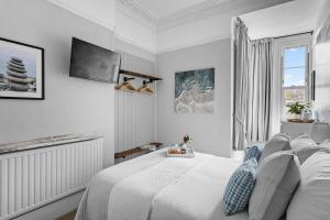 a white bedroom with a bed and a tv at Sandway House in Torquay