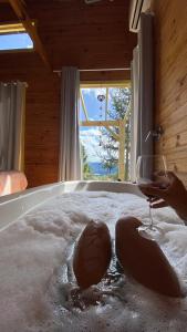 a glass of wine sitting on a bed with snow at Cabana Refúgio - Pousada Colina dos Ventos in Urubici