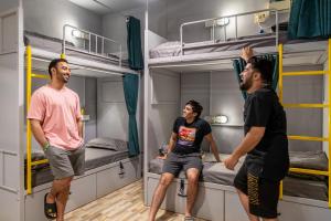 3 Männer stehen in einem Zimmer mit Etagenbetten in der Unterkunft Whoopers Hostel Anjuna, Goa in Anjuna