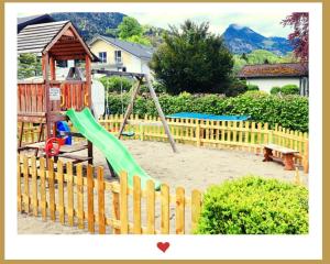 a playground with a green slide in a wooden fence at Berghupferl - do legst di nieda in Oberaudorf