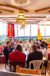 eine Gruppe von Personen, die an Tischen in einem Raum sitzen in der Unterkunft Happy Surf Hostel in Taghazout